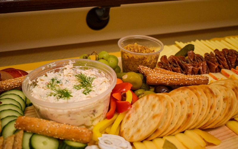 Large charcuterie board with house-made smoked salmon dip, crackers, cheeses and fresh vegetables